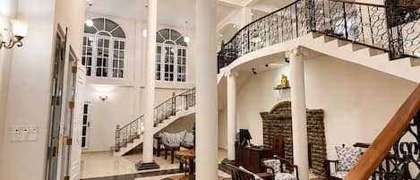 Un vestíbulo amplio con una imponente escalera, techos altos y detalles arquitectónicos clásicos.
