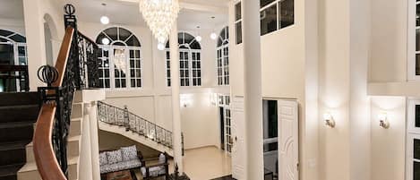 A grand interior with a staircase, a chandelier, and a seating area.