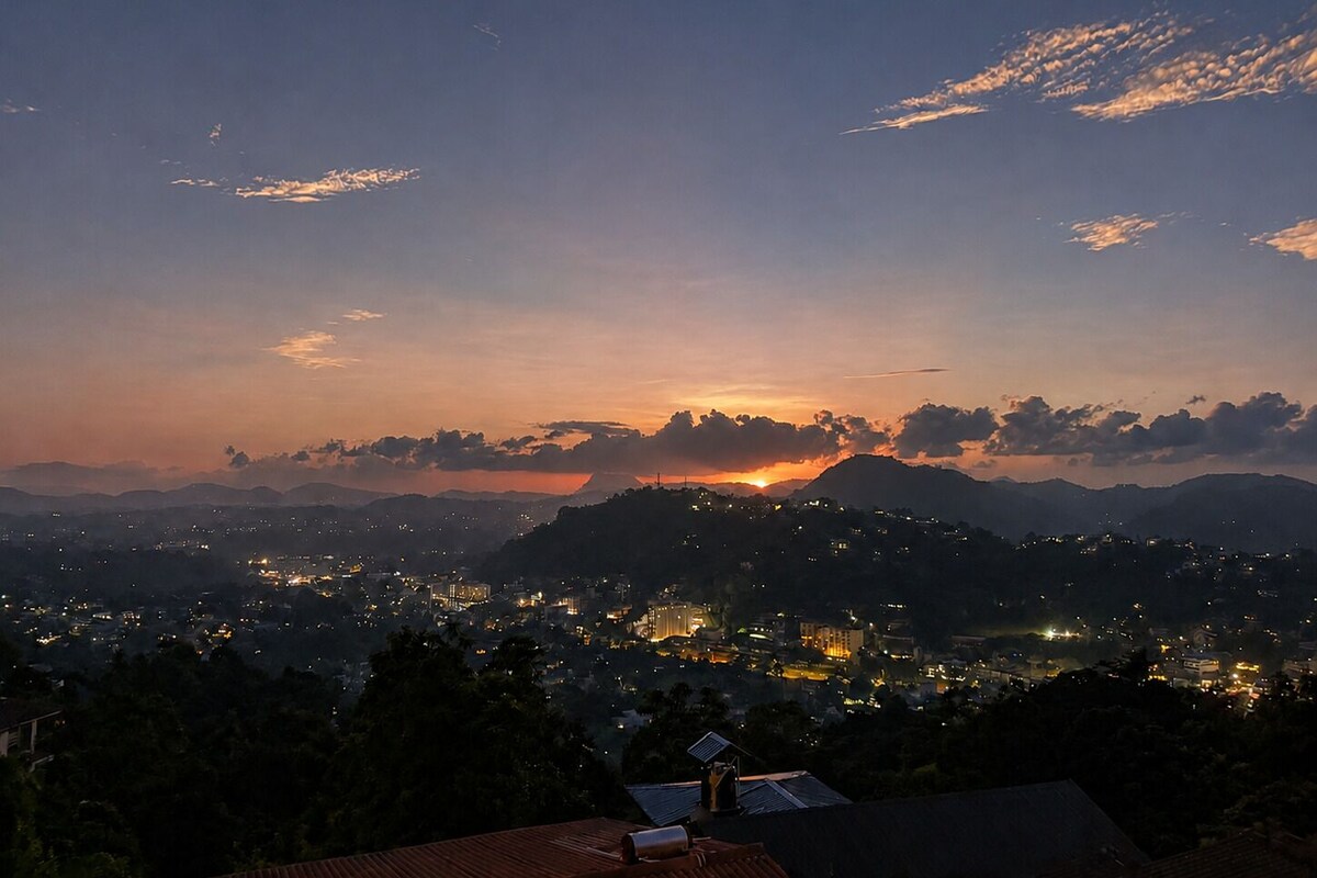 A nighttime cityscape with a sunset, mountains in the background, and a view of a residential area.