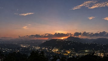 A nighttime cityscape with a sunset, mountains in the background, and a view of a residential area.