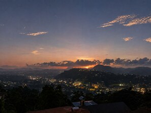 A nighttime cityscape with a sunset, mountains in the background, and a view of a residential area. - ceylon Breeze kandy (Kandy)