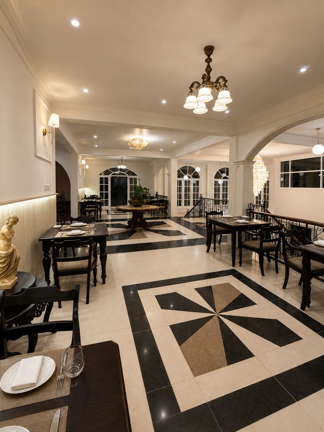 Un comedor espacioso con varias mesas y sillas, un candelabro central y un suelo con diseño.