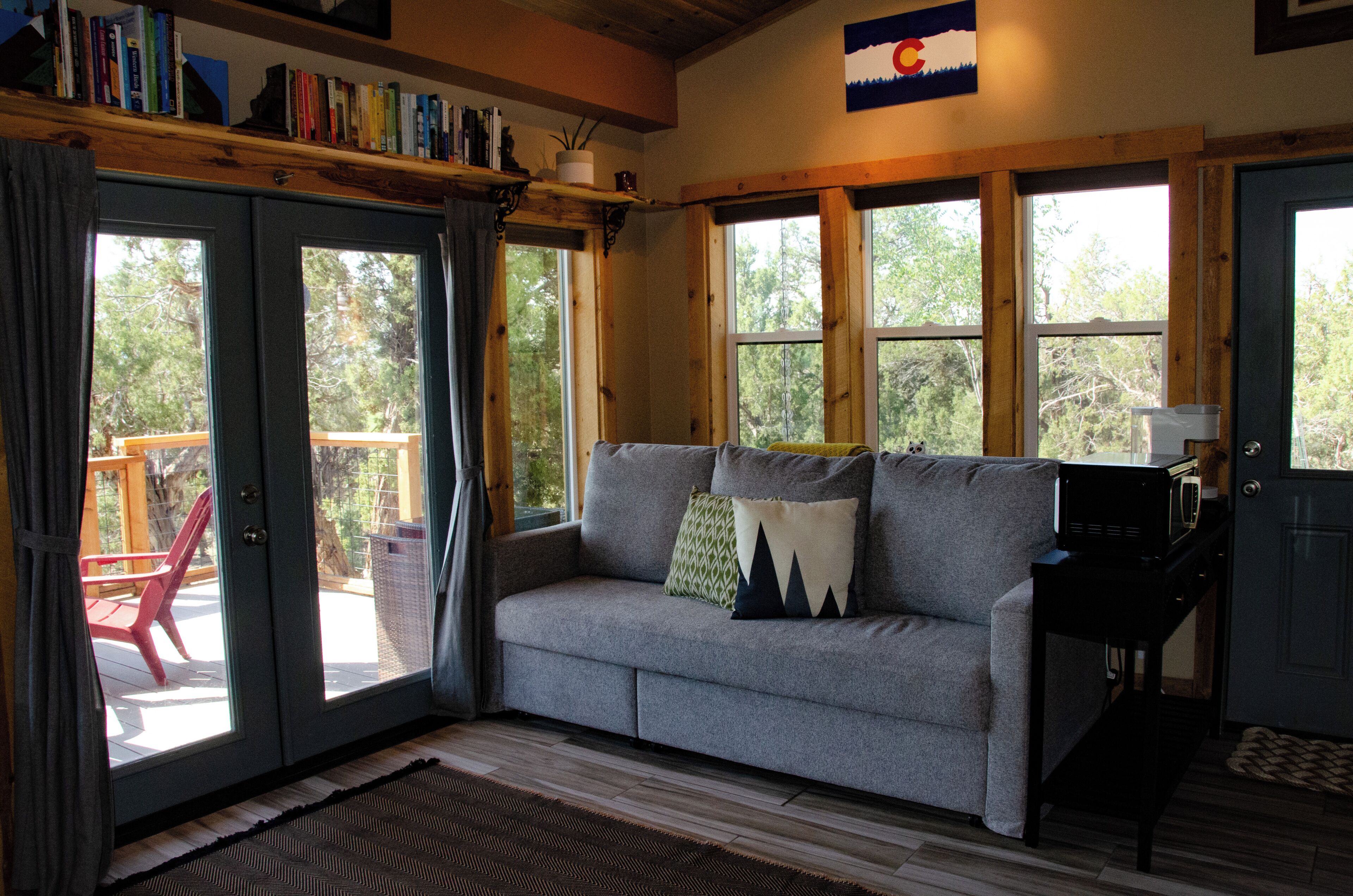 A cozy living room with a grey sofa, a coffee table, and a bookshelf.