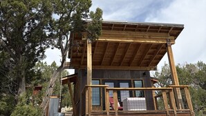 A wooden cabin with a balcony, surrounded by trees. - Stunning Desert Sanctuary - Tiny House with Mesa Verde Views & Starry Nights (Dolores)