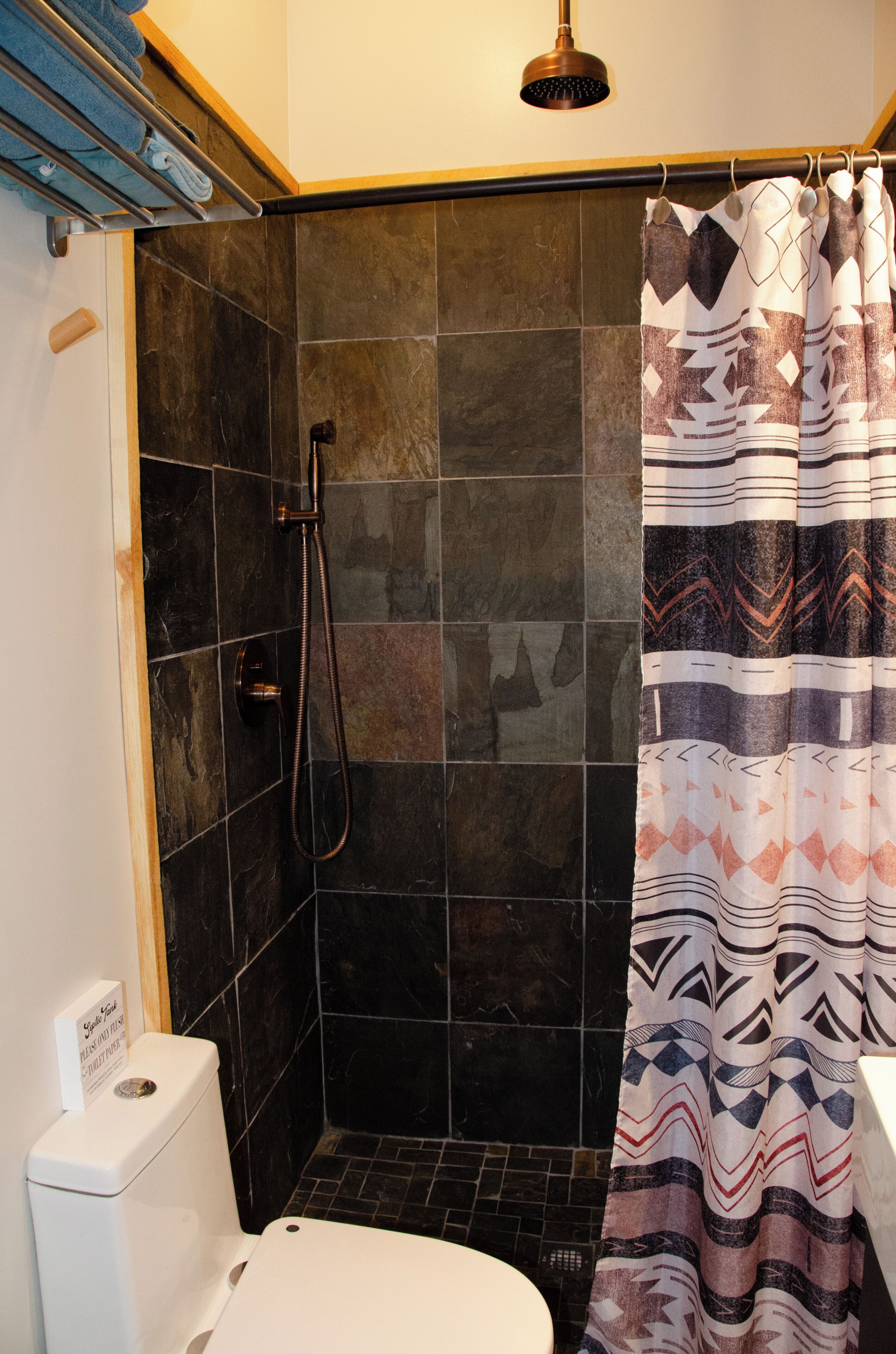 A bathroom with a shower, toilet, and a towel rack.