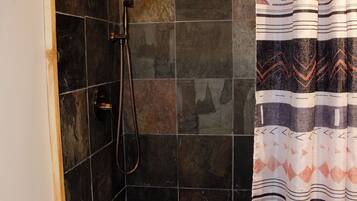 A bathroom with a shower, toilet, and a towel rack.
