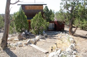 A rustic cabin with a wooden exterior, surrounded by trees and a gravel driveway.
