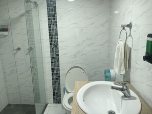 Ein Badezimmer mit Dusche, Toilette und Waschbecken.