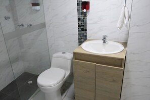 Ein Badezimmer mit Toilette, Waschbecken und Duschbereich.