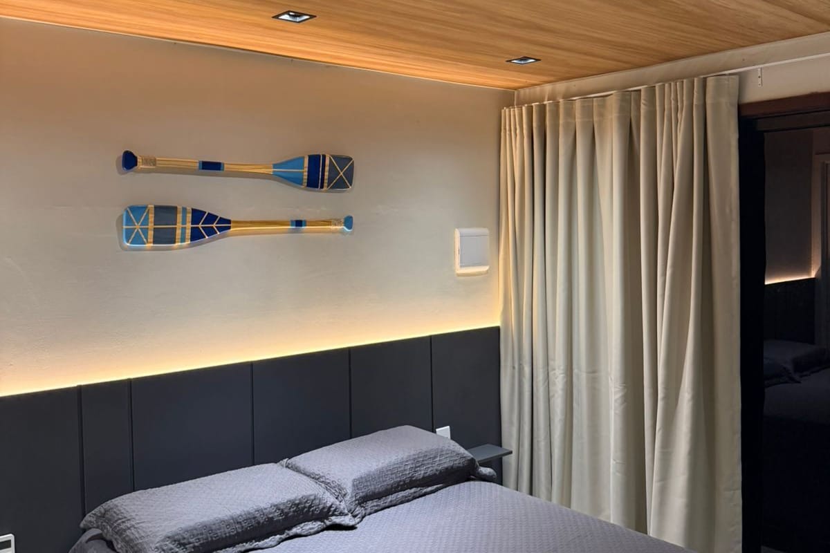 Una habitación de hotel con una cama, una tabla de remo sujeta a la pared y una cortina.