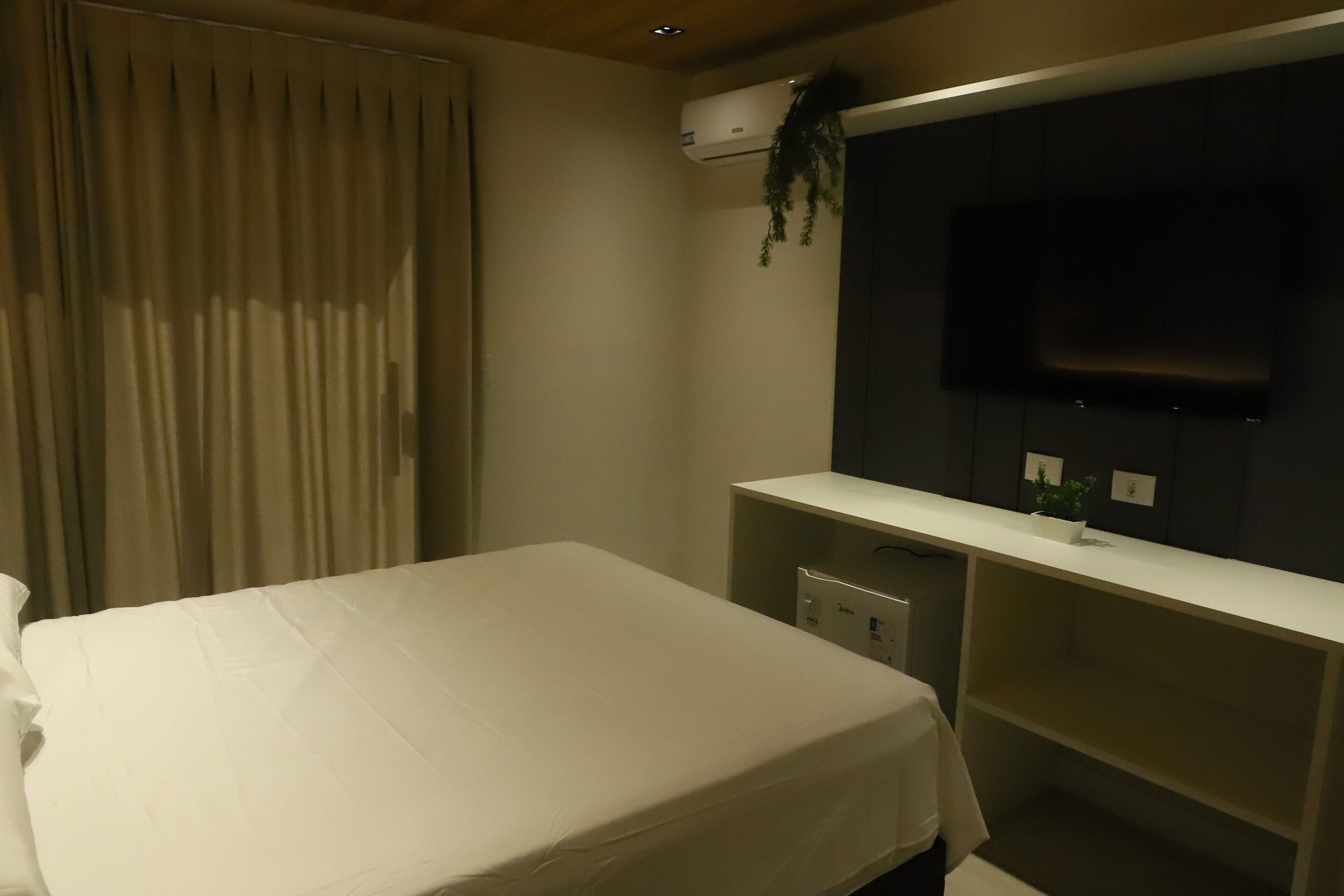 Une chambre d’hôtel équipée d’un lit, d’un bureau et d’un téléviseur fixé au mur.