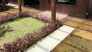 Un espacio al aire libre cubierto con una pérgola de madera, un camino empedrado y un jardín ajardinado con diversas plantas.
