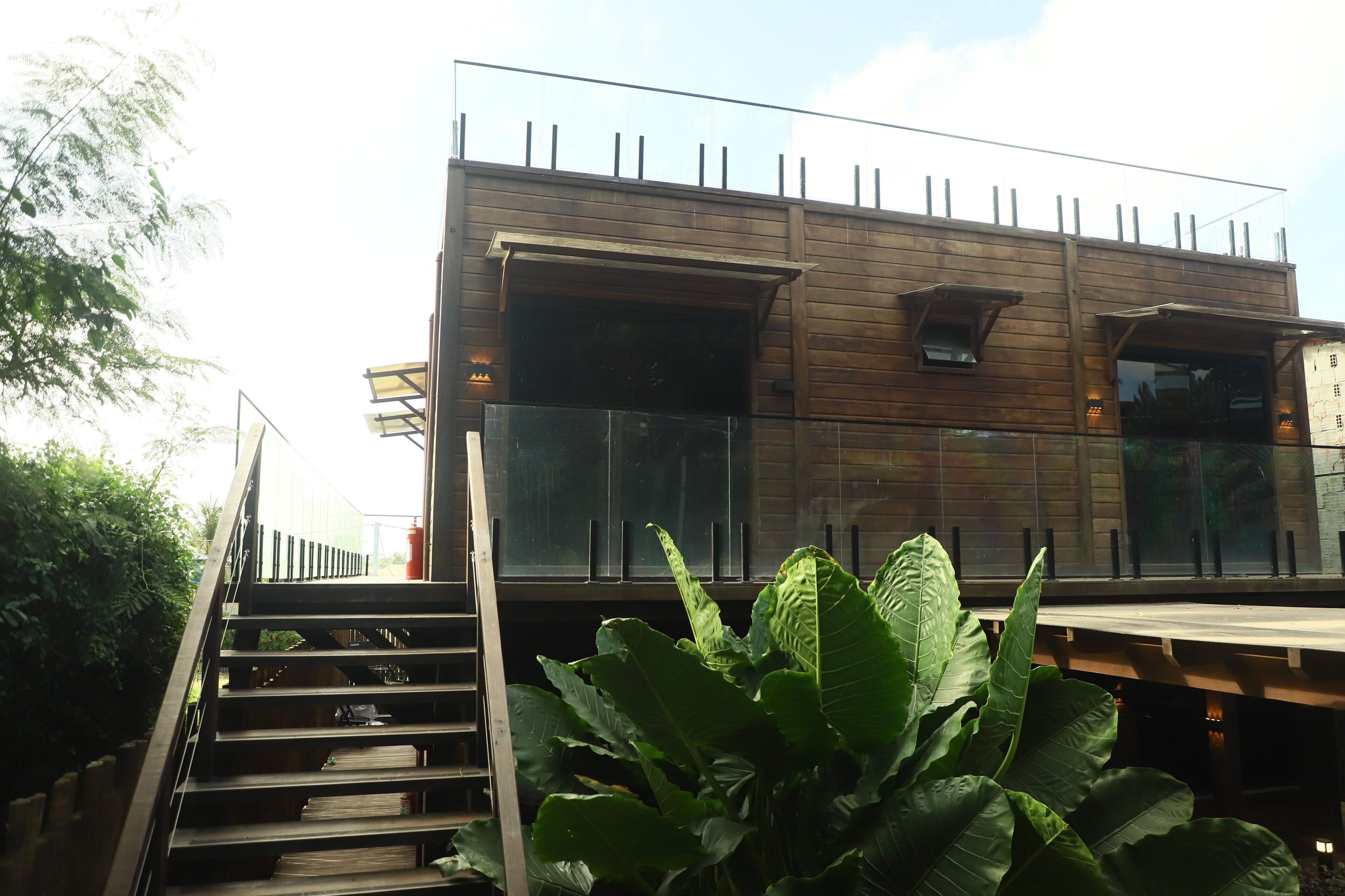 A modern building with a wooden facade, large windows, and a staircase leading to an upper level.
