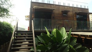Un edificio moderno con fachada de madera, ventanas amplias y una escalera que conduce a un nivel superior.
