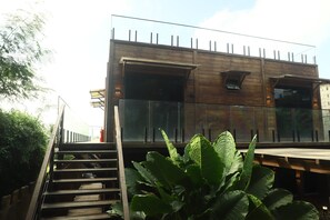 Edifici modern amb façana de fusta, finestres grans i una escala que condueix a un nivell superior.