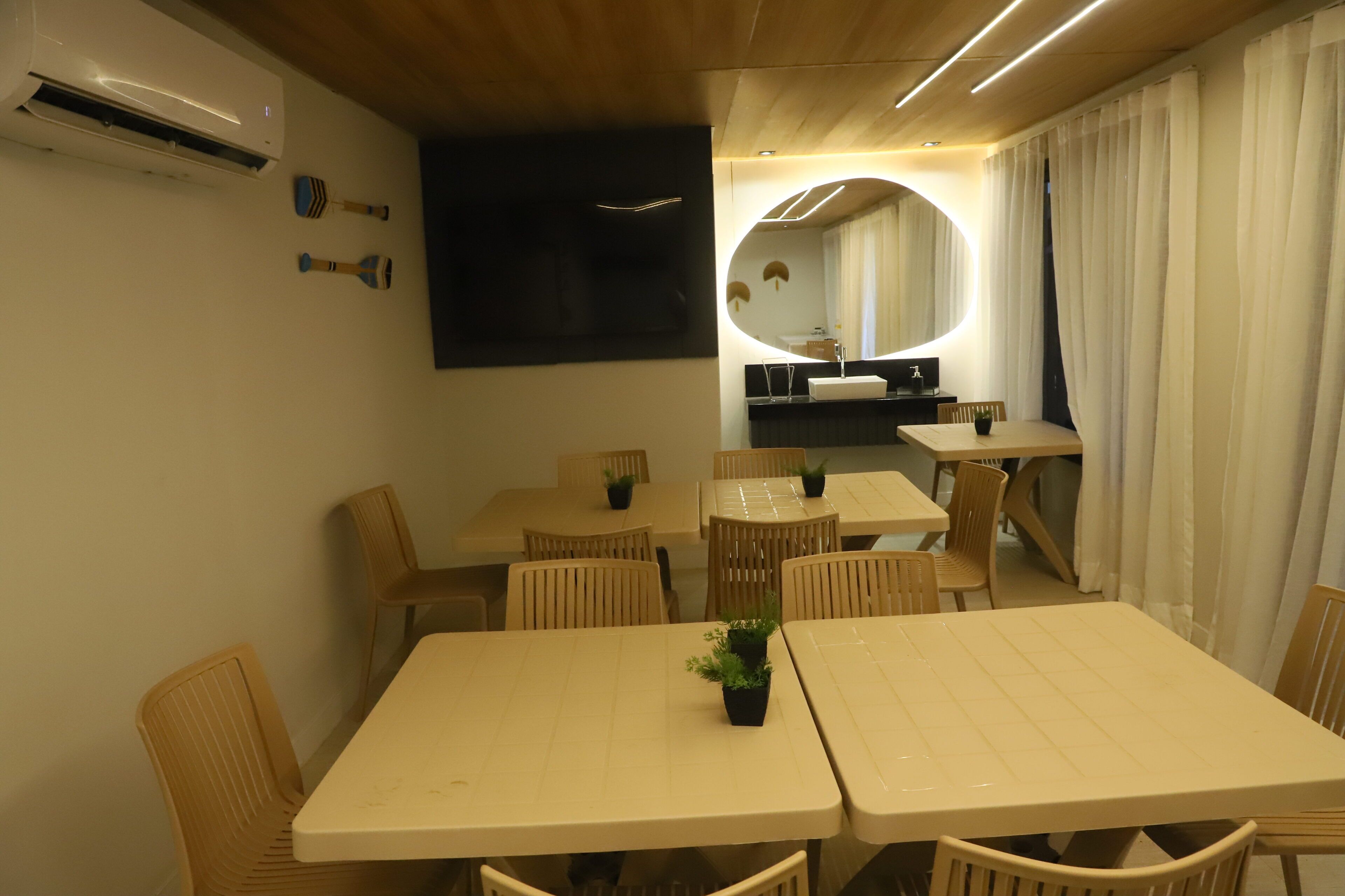 Ein Hotelzimmer mit Essbereich, ausgestattet mit runden Tischen und Stühlen, einem großen Spiegel und einem modernen Design.