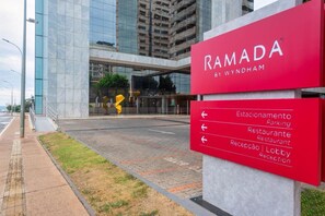 Entrada de un hotel con un cartel que indica servicios como estacionamiento, restaurante y vestíbulo.