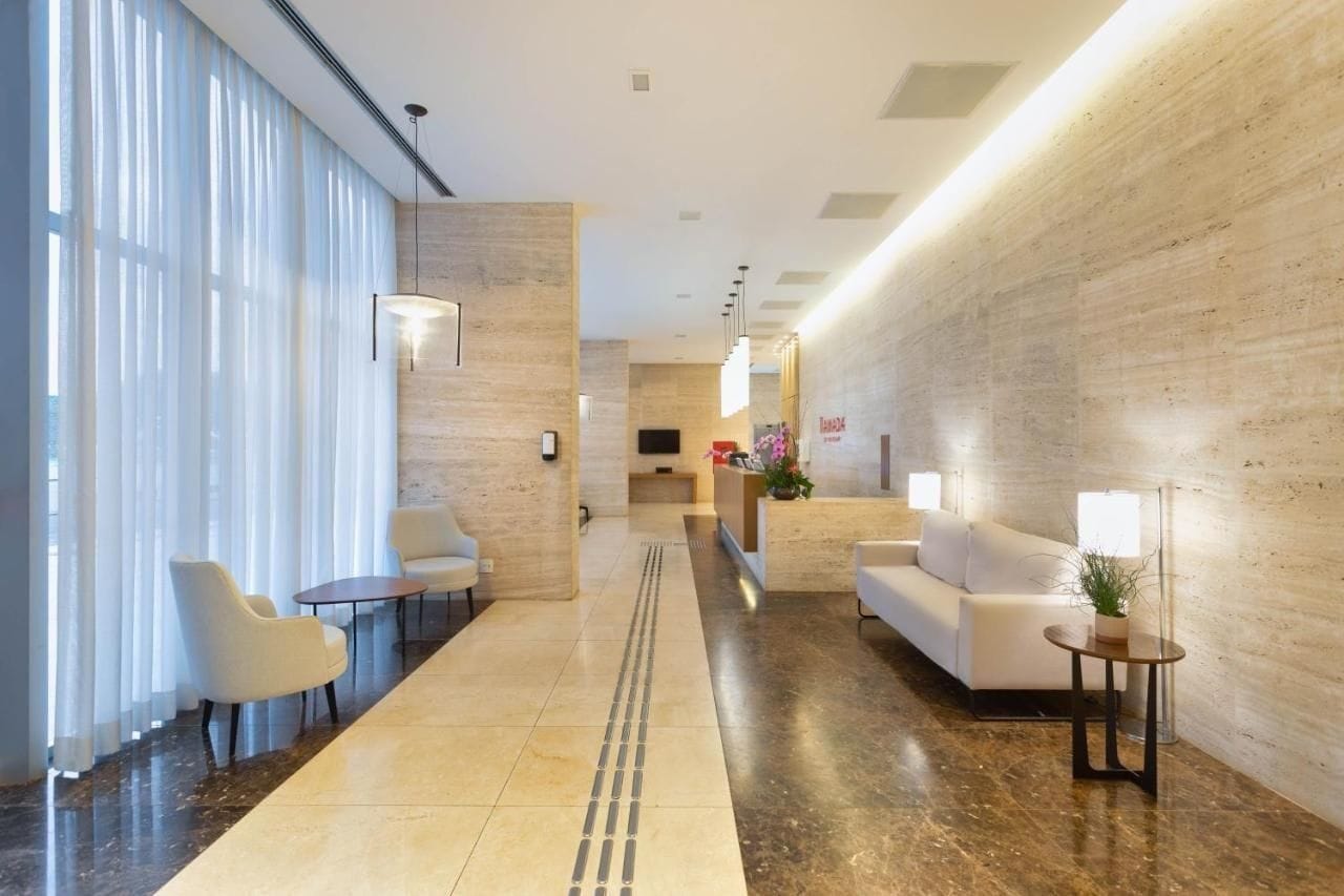 Un hall de hotel con mostrador de recepción, zona de estar y un camino despejado hacia la entrada.