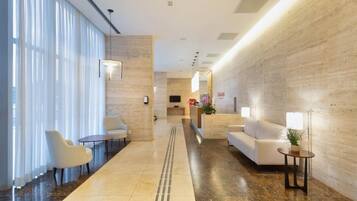 Un hall de hotel con mostrador de recepción, zona de estar y un camino despejado hacia la entrada.