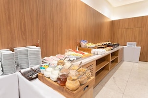 Disposição de buffet com diversos alimentos e utensílios.