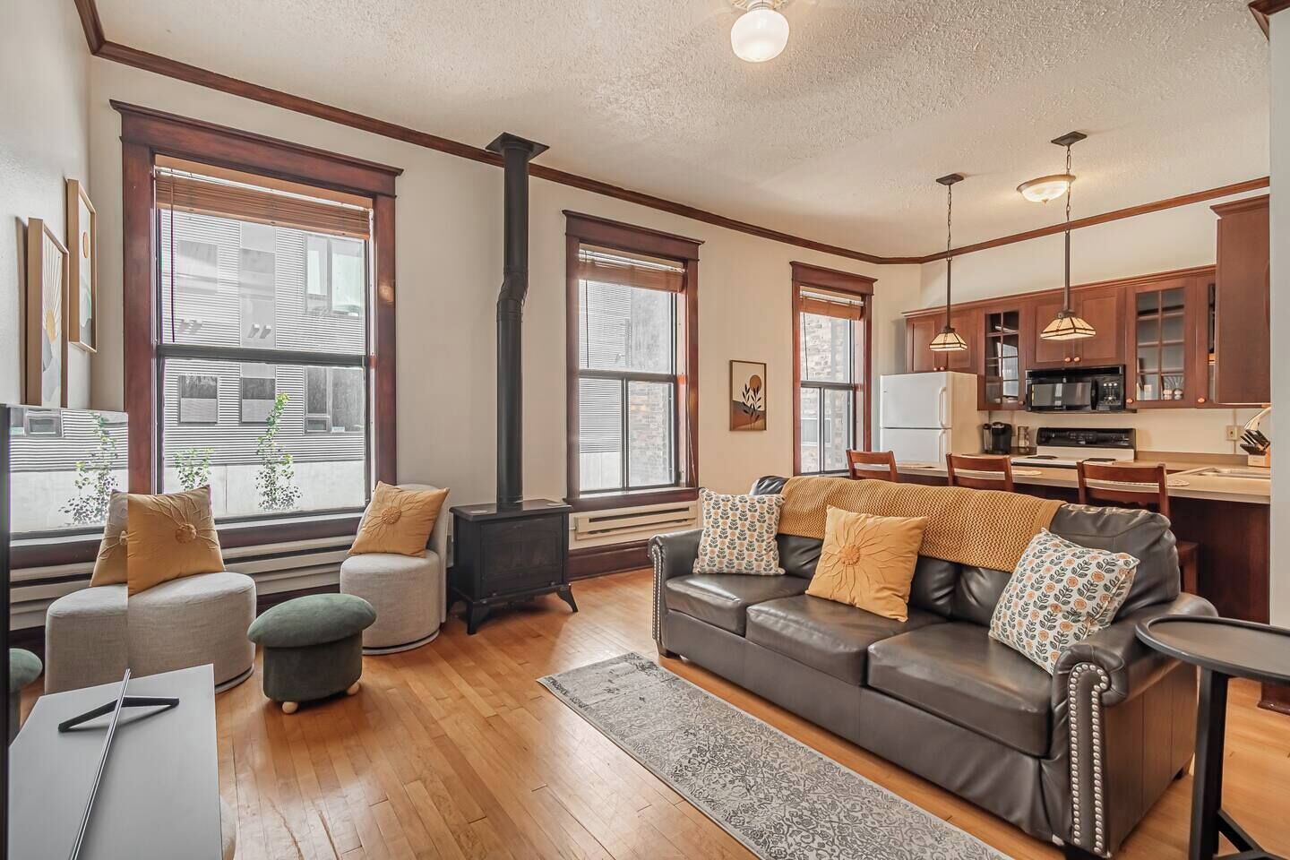 A living room with a fireplace, a sofa, a coffee table, and a dining area with a kitchen in the background.