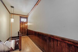 Ein Korridor mit Holzwandverkleidung, einer Holztür mit einer Nummer und einer Leuchte.