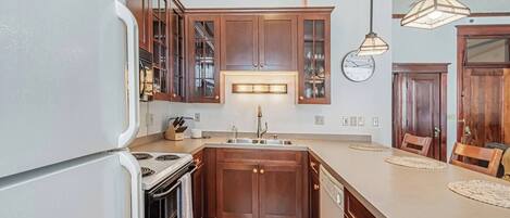 A kitchen with wooden cabinets, a built-in oven, a sink, and pendant lighting.