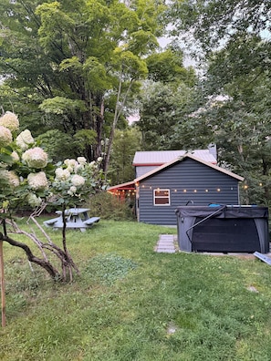 Ein Haus mit überdachter Terrasse, einem Gartenhaus und einem Rasen.