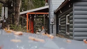 En timmerstuga med en takförsedd uteplats och en bil parkerad framför.
