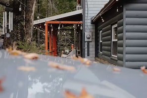 Ein Blockhaus mit überdachter Terrasse und einem geparkten Auto davor.