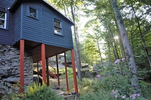 Ein Haus mit steinernen Fundamenten und einer Holzterrasse, gestützt von roten Balken.