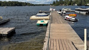 En träbrygga som sträcker sig ut i en sjö, med båtar förtöjda vid dess ände.