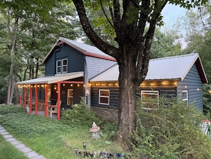 A cabin with a porch, surrounded by trees and a garden. - The Beech Street Bungalow-  Hottub + Pedal Boat (Smallwood)