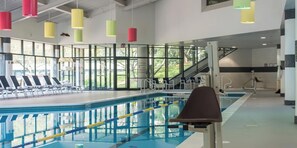 Una piscina con carril, tumbonas y zona de vestuarios.