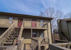 A two-story building with a wooden deck and a staircase leading to the entrance.