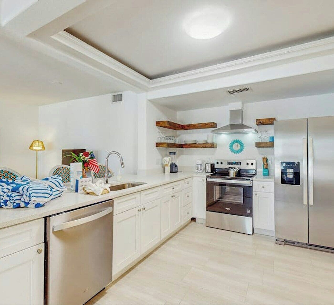 Una cocina moderna con armarios blancos, horno empotrado y refrigerador de acero inoxidable.
