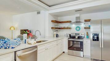 A modern kitchen with white cabinetry, a built-in oven, and a stainless steel refrigerator.