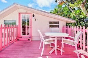 A pink house with a white door, number 3, a small porch, and a white table with chairs.