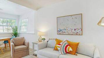 Un salon avec un canapé, un fauteuil, une table basse et un tableau accroché au mur.