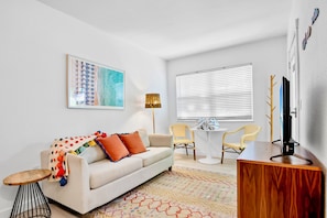A modern living room with a sofa, a coffee table, a TV, and a painting on the wall.