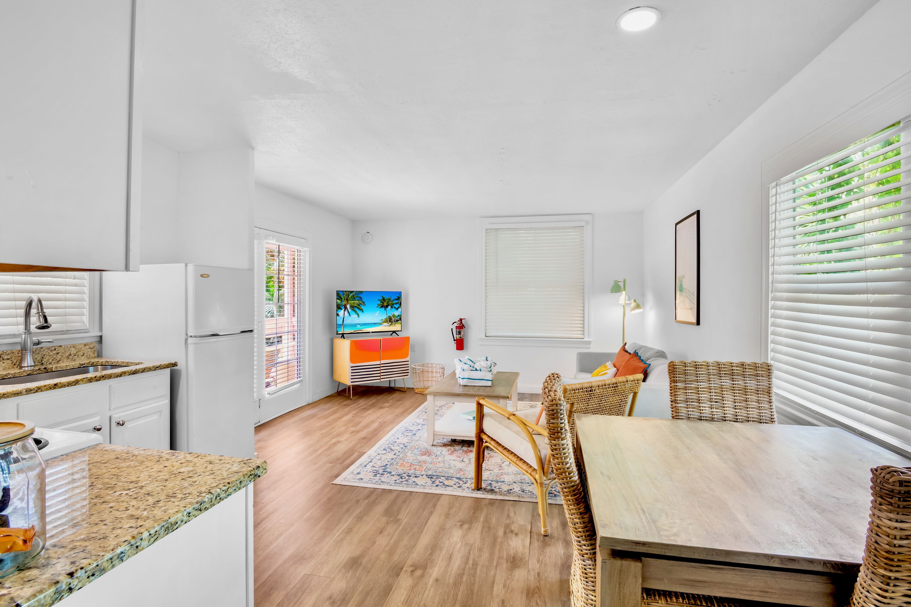 A compact kitchen with a refrigerator, sink, and a dining area with a table and chairs.