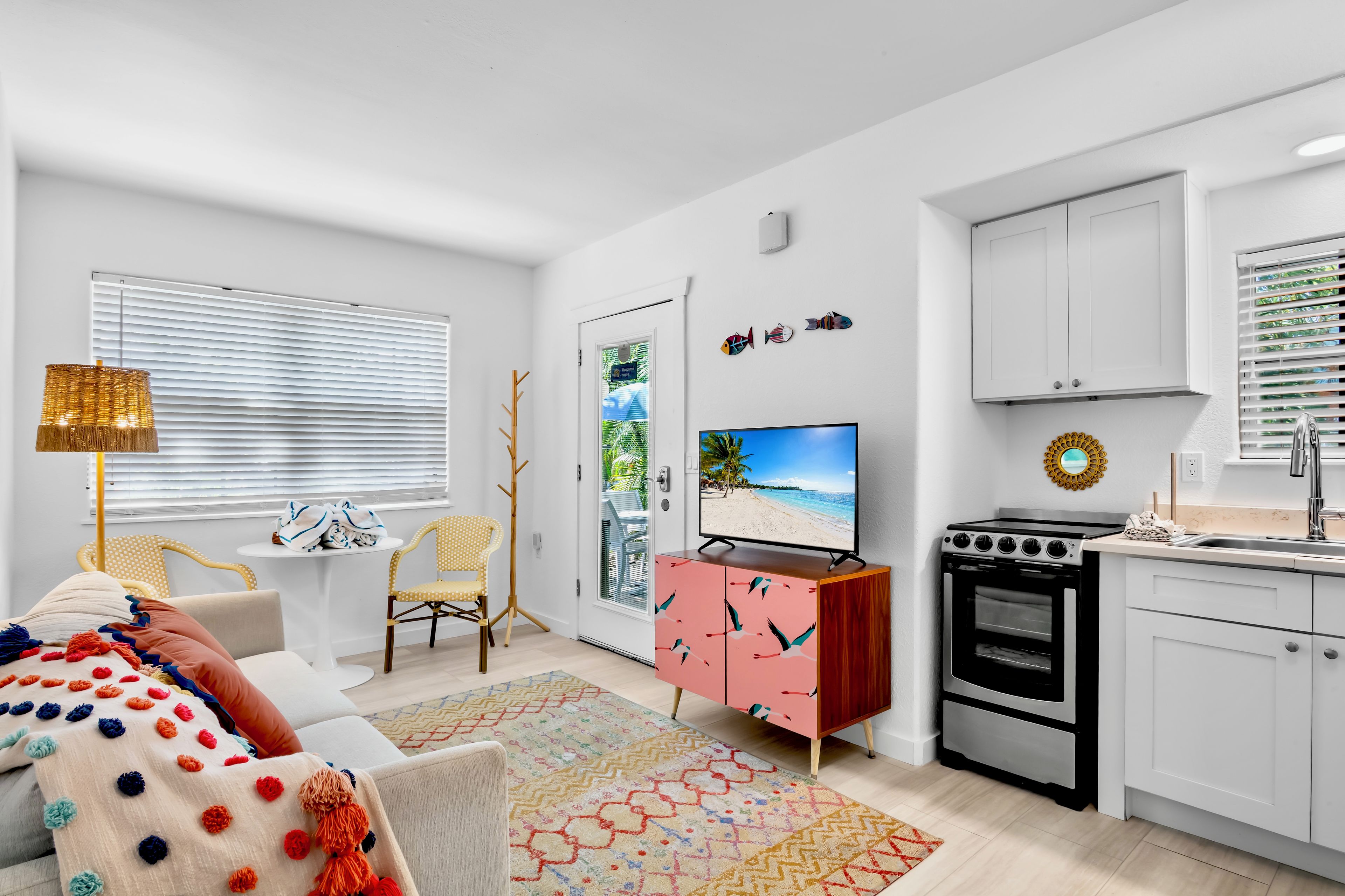 Una sala moderna con un sofá, televisor y una cocina con armarios y estufa.