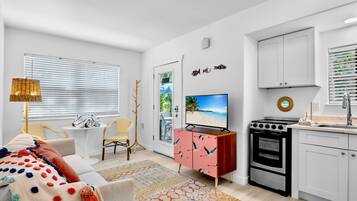 Una sala moderna con un sofá, televisor y una cocina con armarios y estufa.