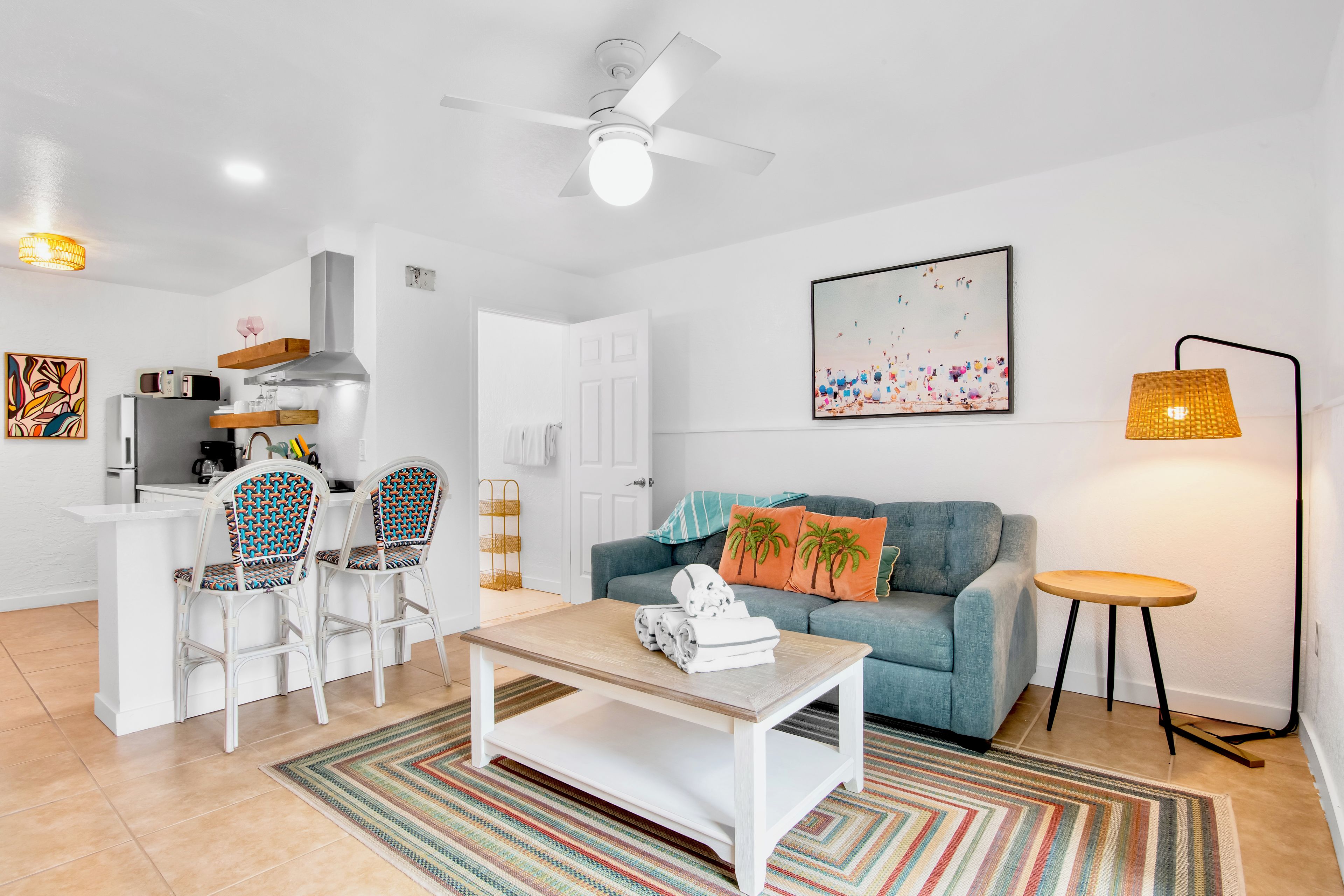 Una sala de estar moderna con sofá, mesa de centro, sillas y un comedor con microondas y refrigerador.