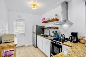 A modern kitchen with white cabinetry, a stainless steel range hood, a built-in oven, and a granite countertop.