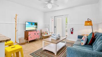 A modern living room with a television, a sofa, a coffee table, and a dining area.