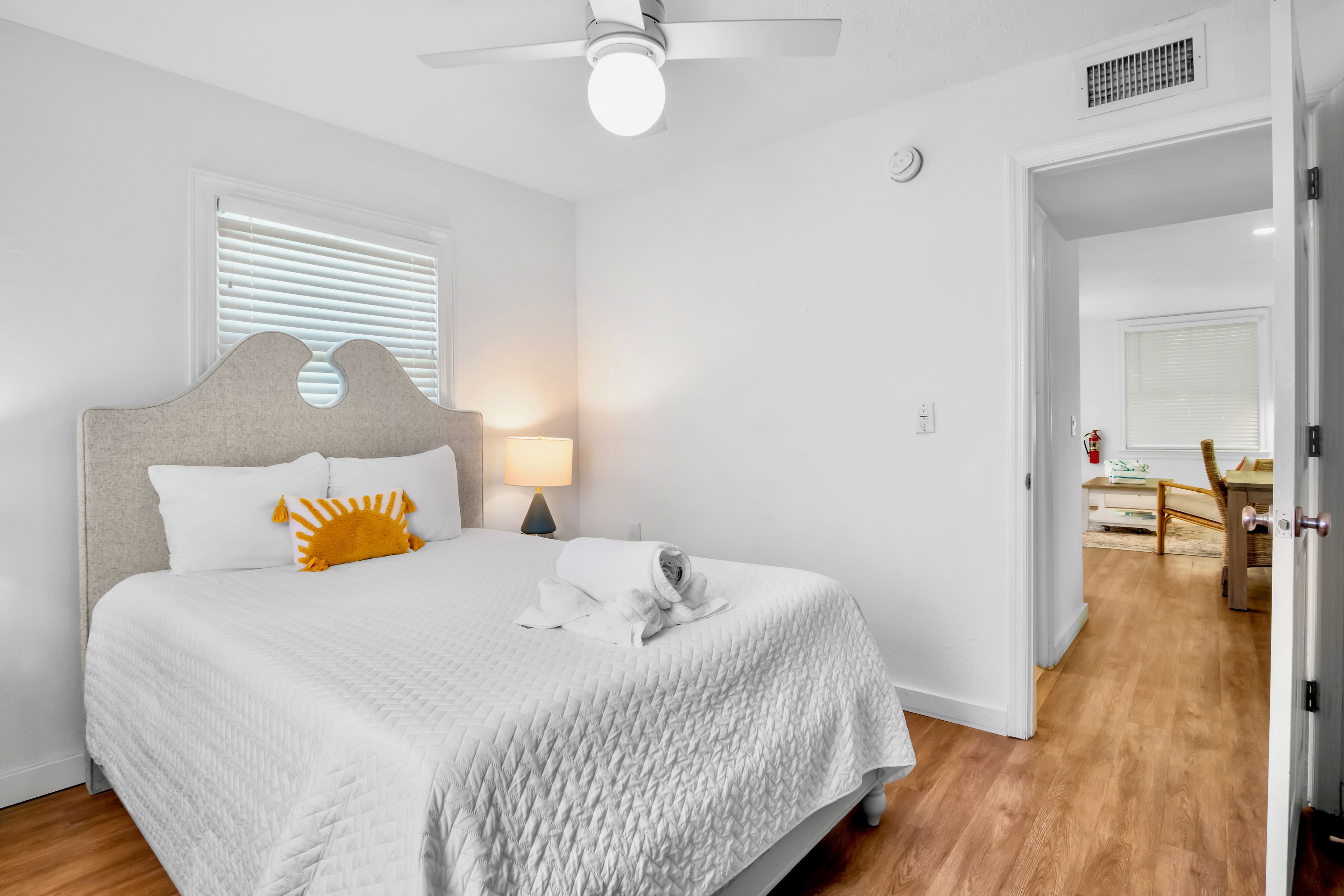 Un dormitorio con cama, mesita de noche, lámpara y ventilador de techo.