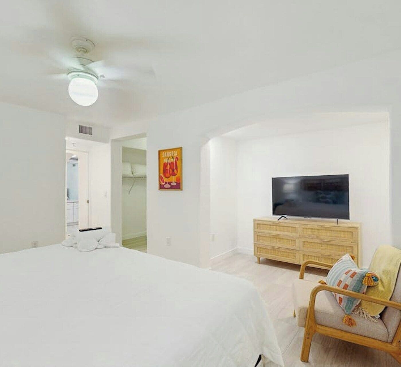 A bedroom with a bed, a television on a wooden dresser, a chair, and a poster on the wall.