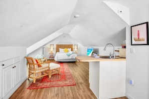A compact, modern apartment with a loft bedroom, a small kitchenette, and a dining area.