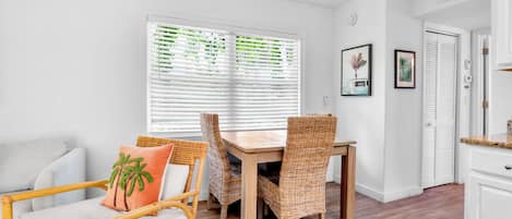 Una habitación con una mesa de comedor, sillas, un sofá y una ventana con persianas.